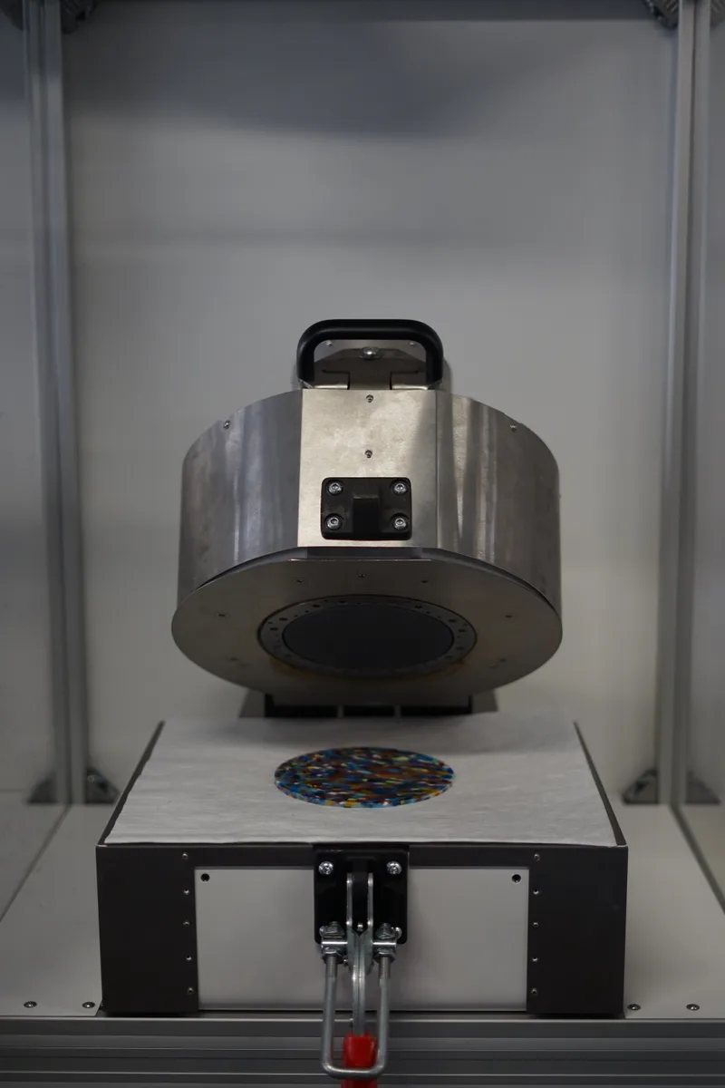 MADSCAN close-up with the upper assembly raised above a multicoloured plastic sample.